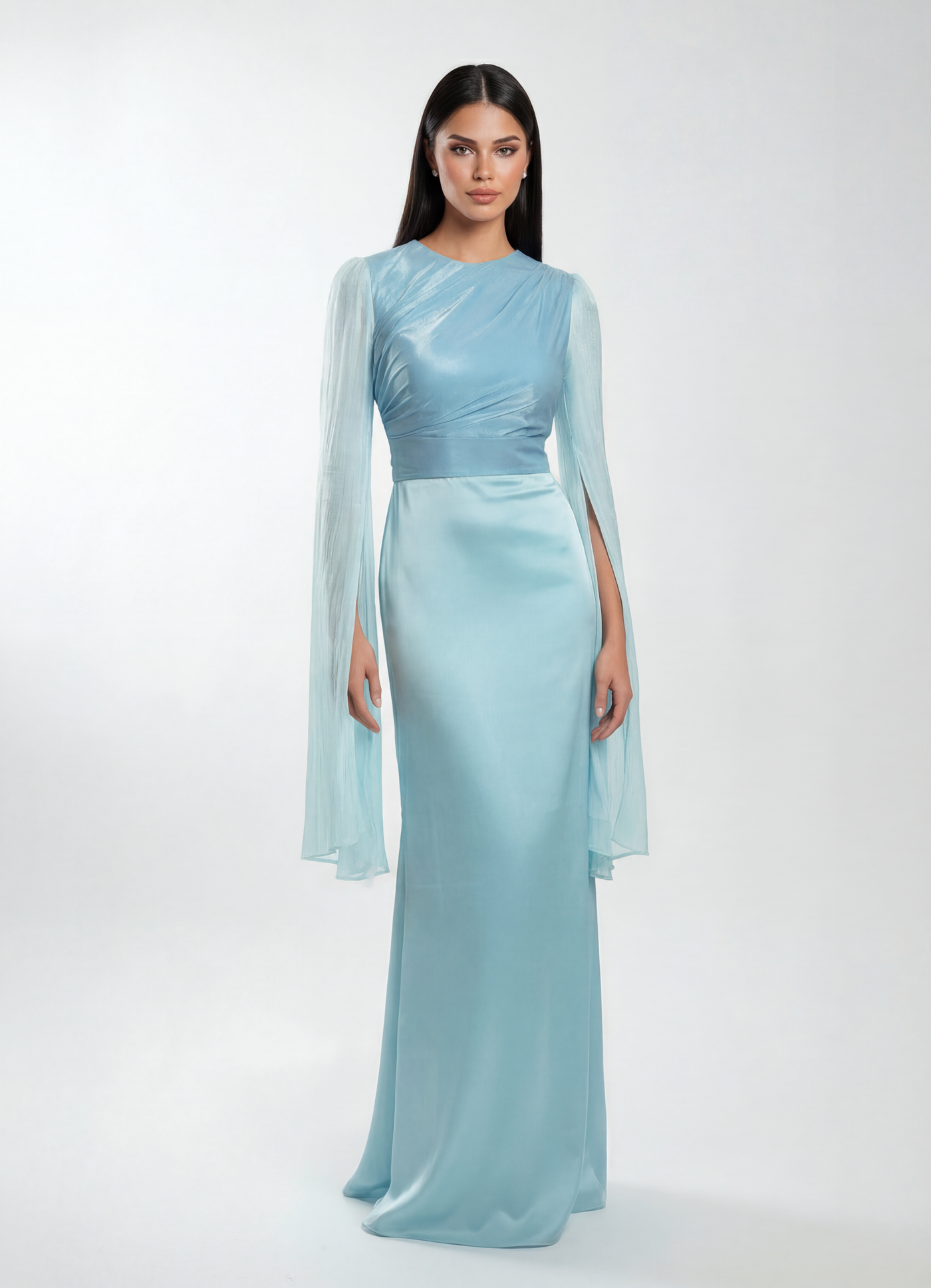 Woman wearing a light blue evening gown with sheer sleeves on a white background