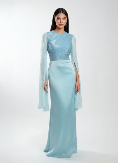 Woman wearing a light blue evening gown with sheer sleeves on a white background