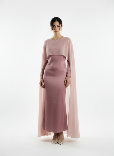 Woman wearing a pink dress with cape on a white background