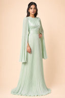 Modest Pleated Satin Gown in Mint Green — three-quarter front angle showing dimensional drape and silhouette — modeled without hijab — modest evening fashion for all — Mystic Modesty modest evening gown collection.