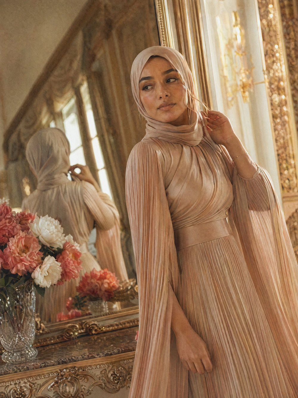 Mystic Modesty SS26— Saffira Champagne pleated satin, intimate dressing-room moment with gilded mirror reflection, modest evening wear, Vogue editorial film aesthetic