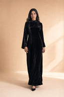 Velvet Elegance Modest Abaya Dress in Deep Black — walking lifestyle shot, confident and graceful arrival — modeled without hijab — modest evening fashion for all — Mystic Modesty hijabi-friendly evening wear.