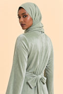Velvet Elegance Modest Abaya Dress in Forest Green — over-shoulder back profile portrait, intimate editorial close-up — modeled with hijab — Islamic modest styling — Mystic Modesty modest evening dress.