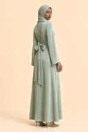 Velvet Elegance Modest Abaya Dress in Forest Green — three-quarter back angle with gentle over-shoulder glance — modeled with hijab — Islamic modest styling — Mystic Modesty modest evening gown collection.